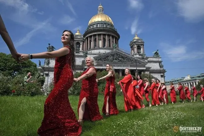 Участницы в красных платьях выстроились в форме сердца в центре города. Проект зародился в Красноярске; участие было платным. Организатор — Элеонора Шипулина.